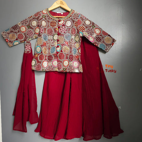 Traditional outfit with a patterned top and red skirt on a gray background