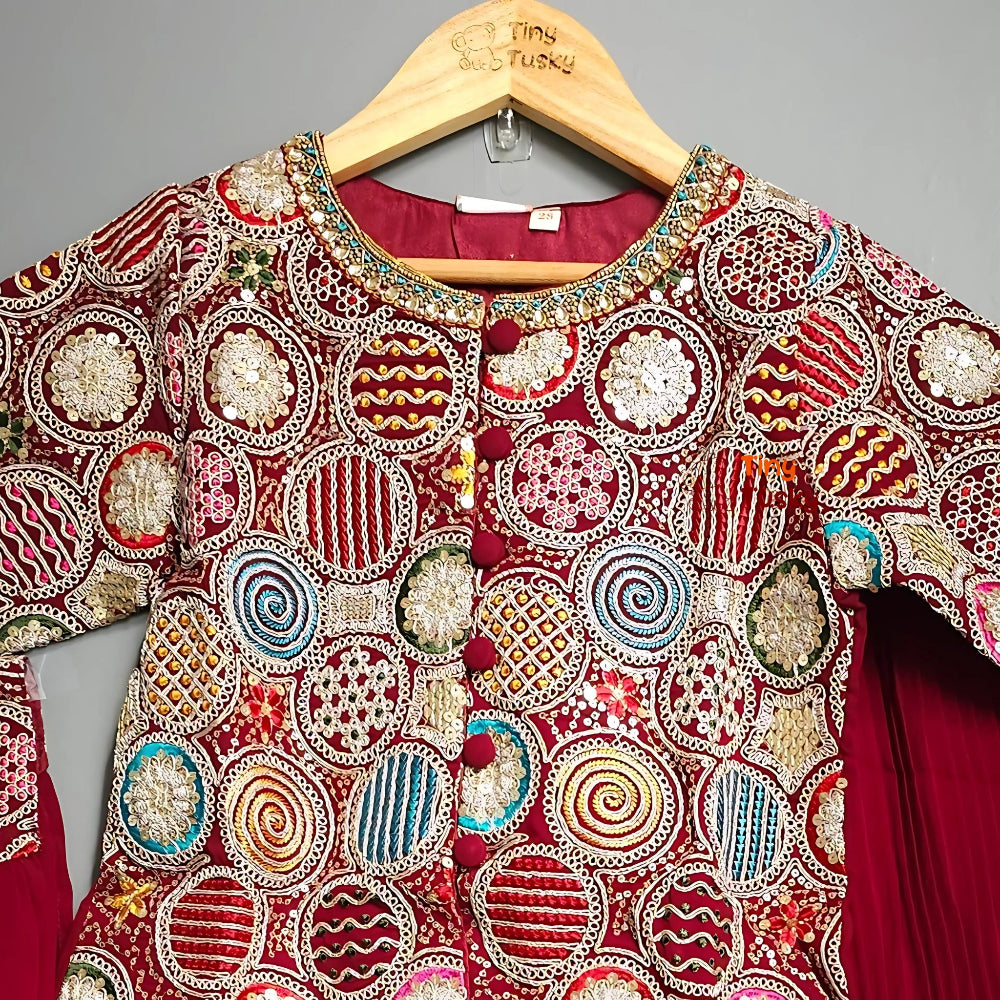 Decorative red garment with intricate patterns on a hanger against a gray background