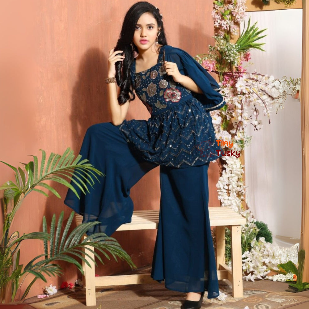 Woman in a blue outfit sitting on a bench with floral decorations in the background