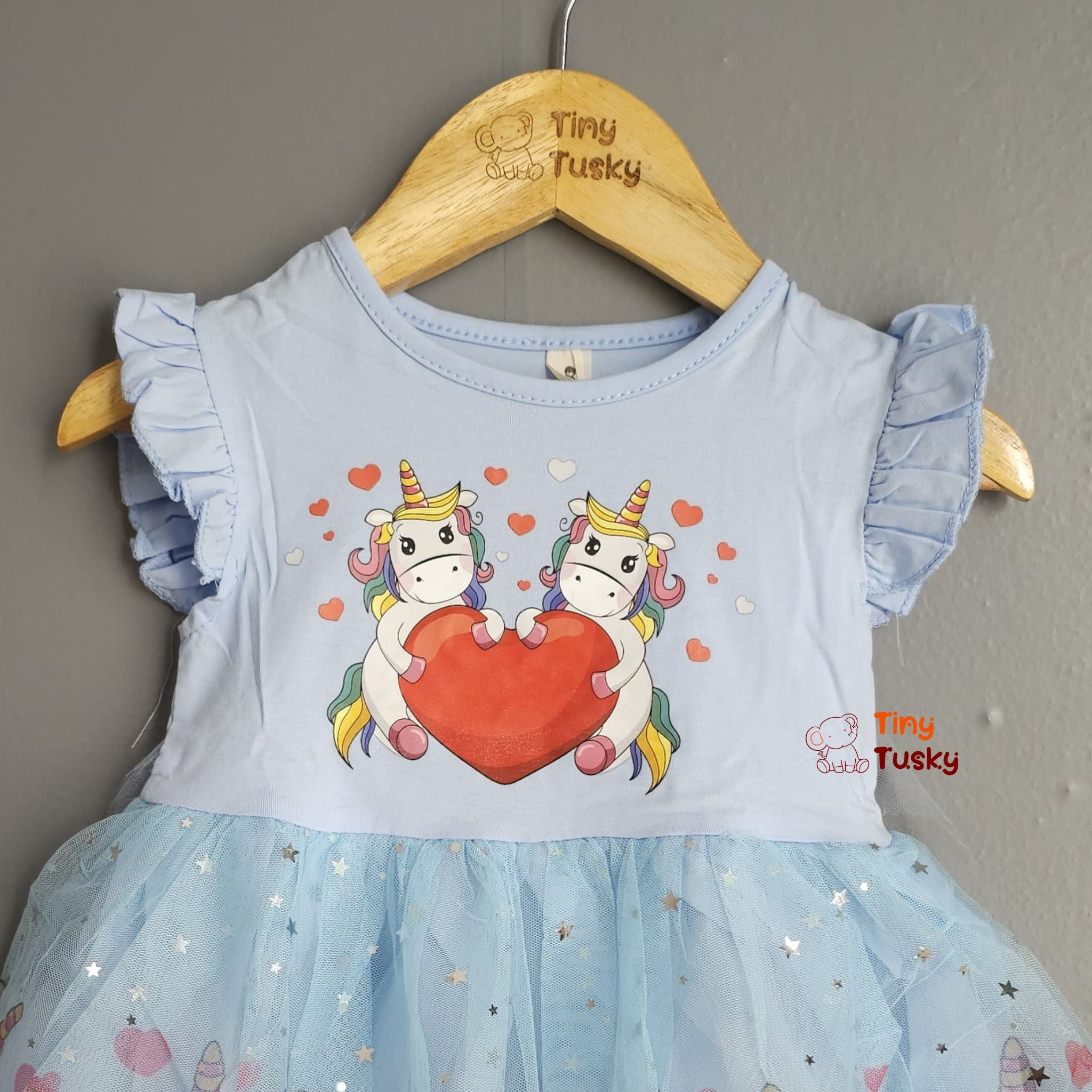 Children's dress with unicorn design on a hanger, brand 'Tiny Tusky' visible