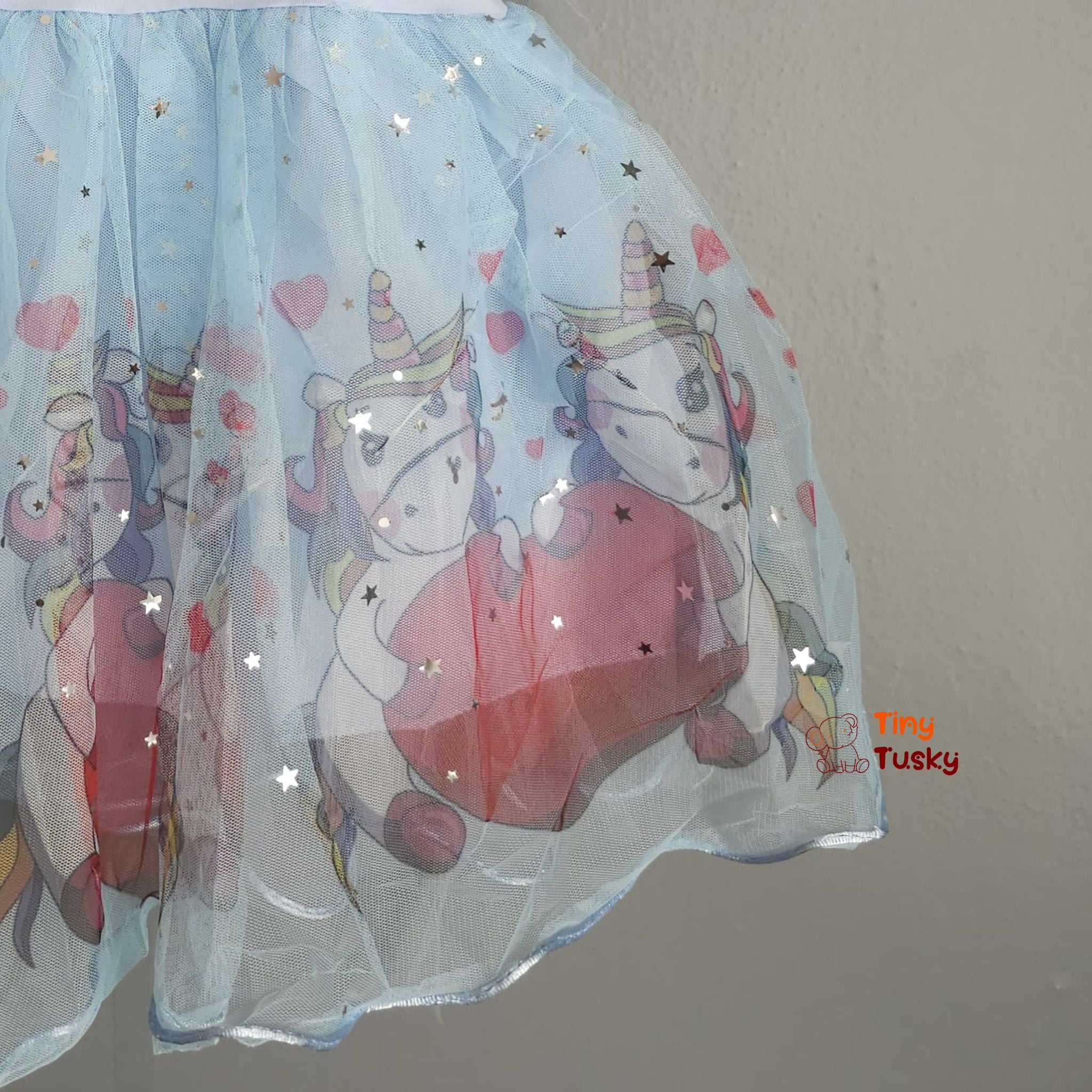 Sheer fabric with unicorn designs and stars on a plain background