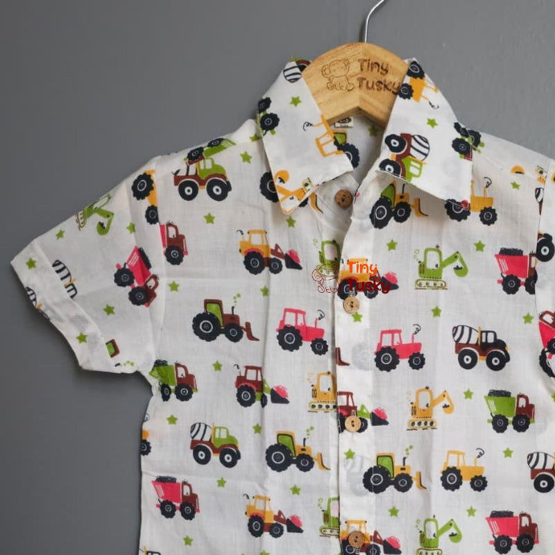 Children's shirt with truck pattern on a hanger against a gray background
